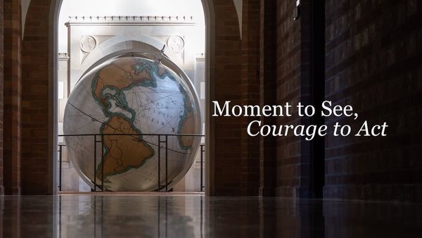 a large globe in a building atrium next to the words Moment To See Courage To Act
