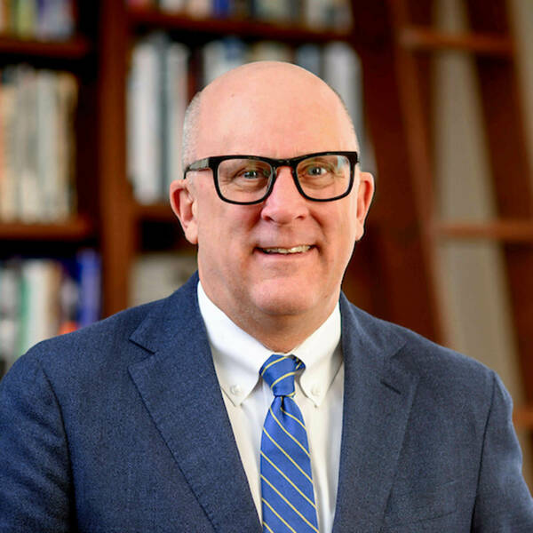 Provost John McGreevy stands in front of a bookcase